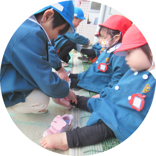 園児同士で靴を履かせている様子